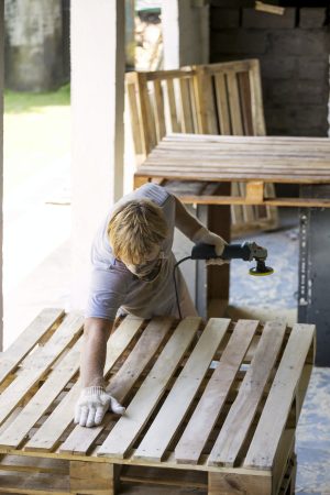 Man sanding pallet with a random orbital sander