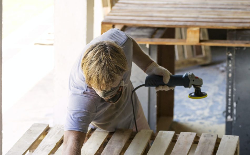 Man sanding pallet with a random orbital sander